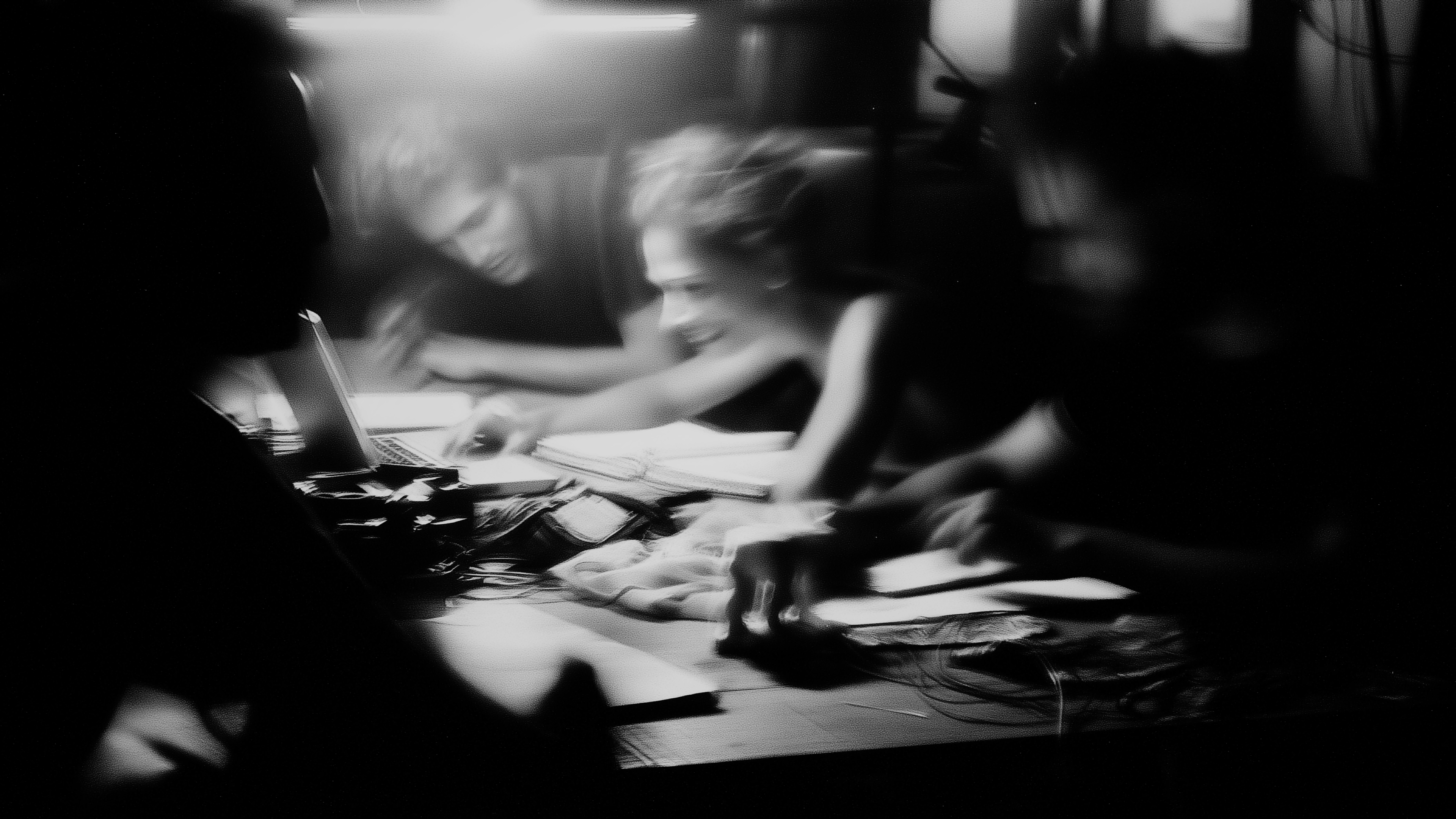 An anonymous group of creators working together around a table with a laptop, papers, textiles, and electronic materials.